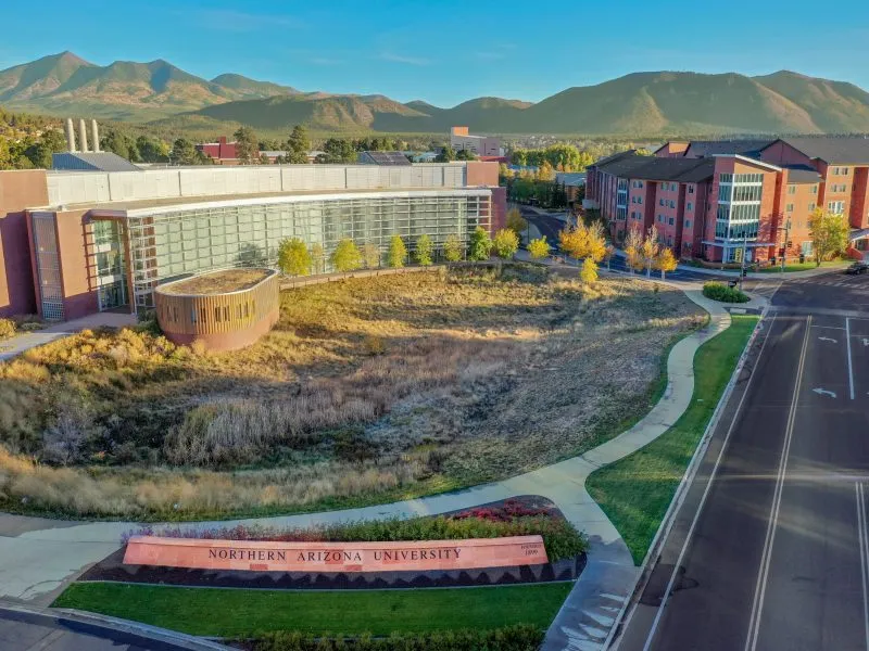 Aerial view of native grasses and a curving path in front of a campus building at Northern Arizona University